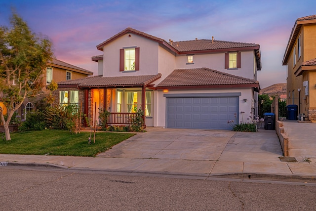 mediterranean / spanish home featuring a porch, a garage, and a yard