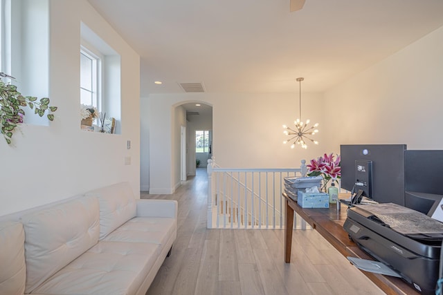 office with a notable chandelier, light wood-type flooring, and a wealth of natural light