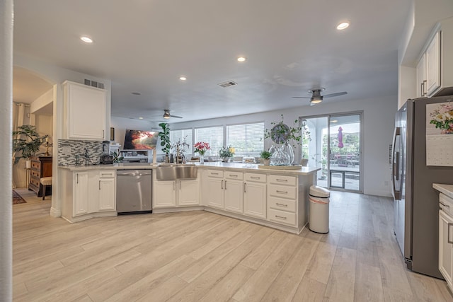 kitchen featuring kitchen peninsula, sink, appliances with stainless steel finishes, tasteful backsplash, and white cabinetry