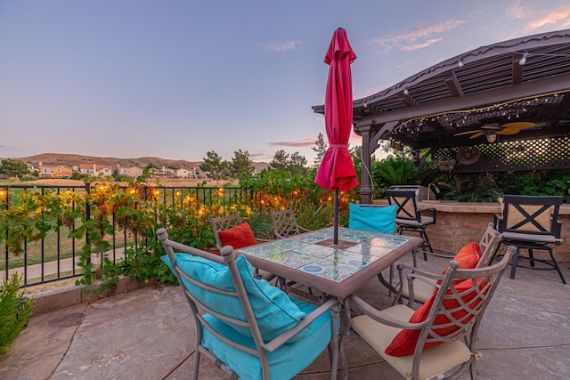 patio terrace at dusk featuring a mountain view and ceiling fan