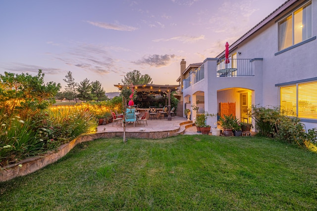 yard at dusk featuring a pergola, a balcony, and a patio area