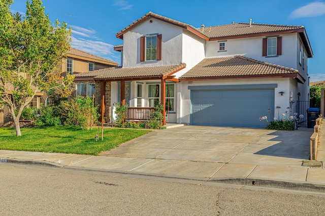 mediterranean / spanish home with covered porch, a front yard, and a garage