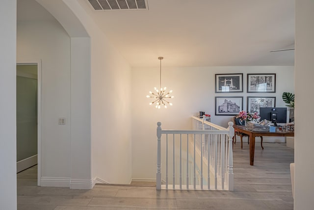 corridor with light hardwood / wood-style flooring and a chandelier