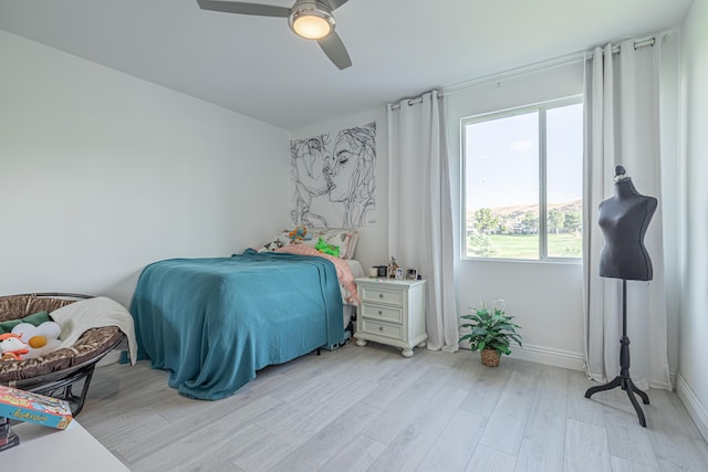 bedroom featuring ceiling fan, light hardwood / wood-style floors, and multiple windows