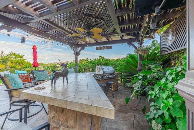 view of patio featuring ceiling fan, exterior kitchen, a pergola, grilling area, and exterior bar