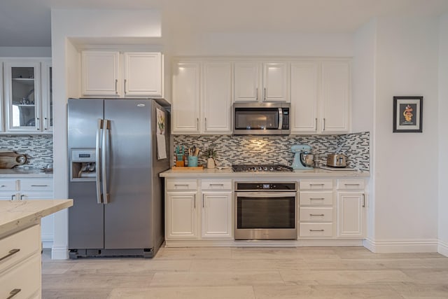 kitchen with white cabinets, decorative backsplash, and stainless steel appliances