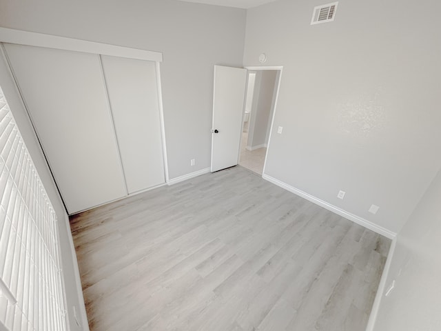 unfurnished bedroom featuring light wood-type flooring and a closet