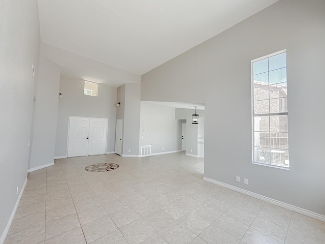 unfurnished room with a towering ceiling and light tile patterned flooring