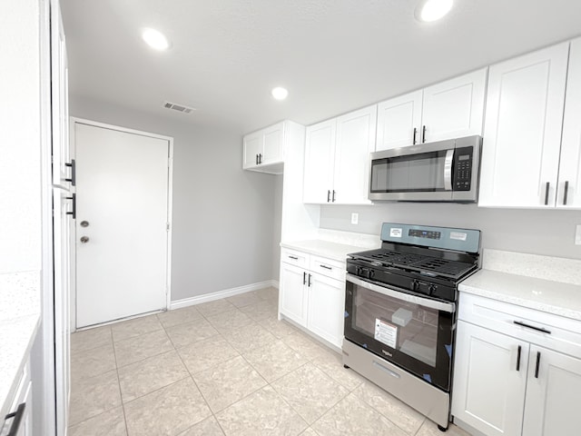 kitchen with light stone countertops, appliances with stainless steel finishes, light tile patterned floors, and white cabinetry