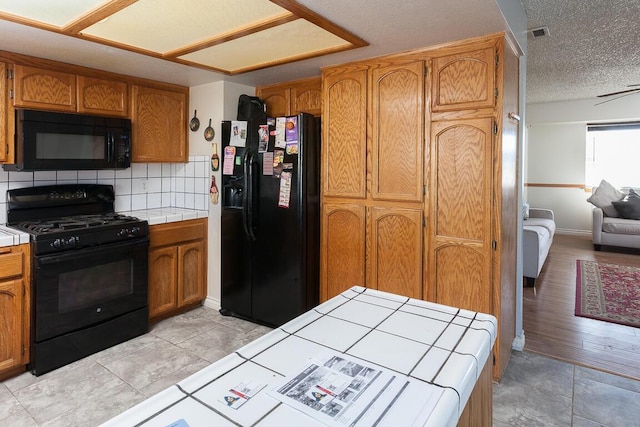 kitchen featuring ceiling fan, black appliances, tile countertops, and tasteful backsplash