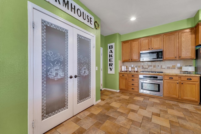 kitchen featuring light stone counters, backsplash, stainless steel appliances, and french doors