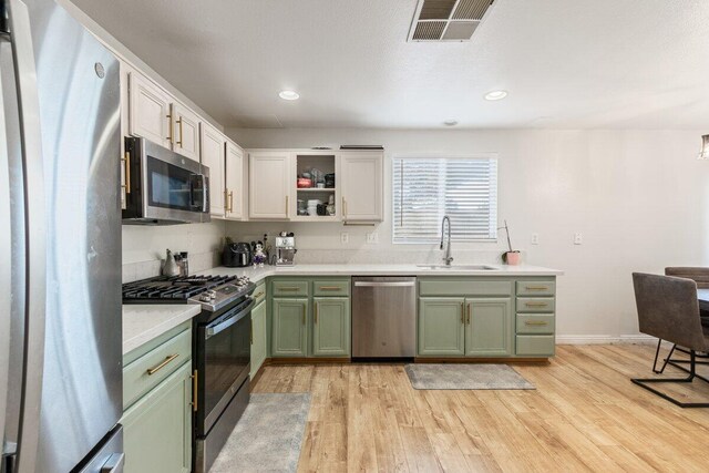 40305 Reata Rd, Palmdale, CA 93550 - kitchen featuring green cabinets, appliances with stainless steel finishes, a sink, light wood-type flooring, and light countertops