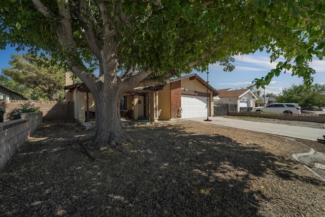 view of front of property with a garage, brick siding, concrete driveway, and fence