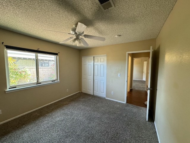 unfurnished bedroom featuring a textured ceiling, visible vents, baseboards, a closet, and carpet