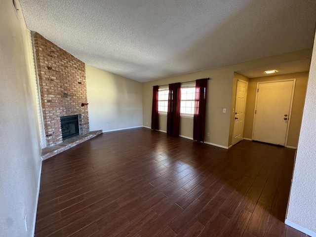 unfurnished living room with a fireplace, baseboards, dark wood finished floors, and a textured ceiling