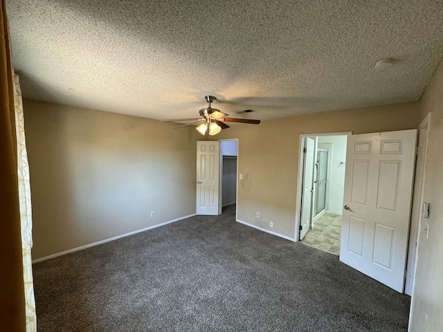 unfurnished bedroom with baseboards, ensuite bathroom, a walk in closet, carpet flooring, and a closet