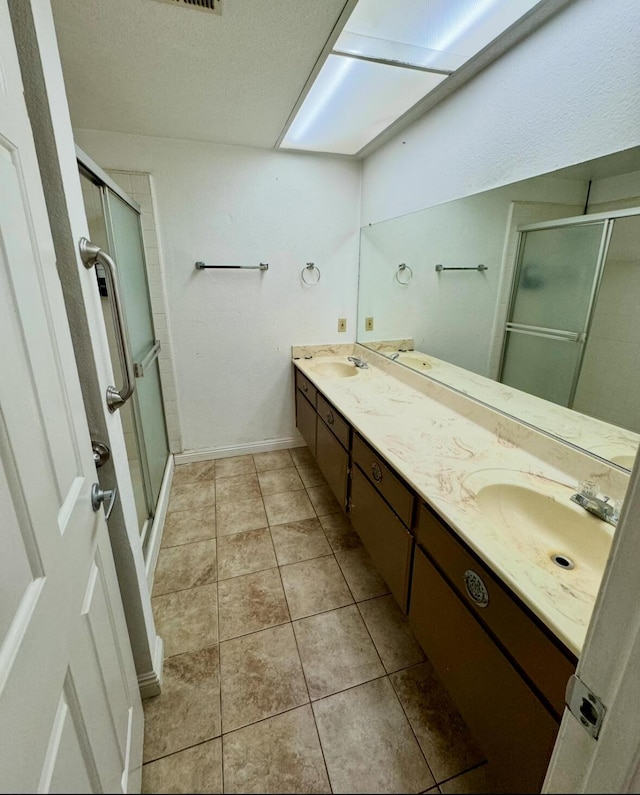 full bathroom with double vanity, a stall shower, and a sink