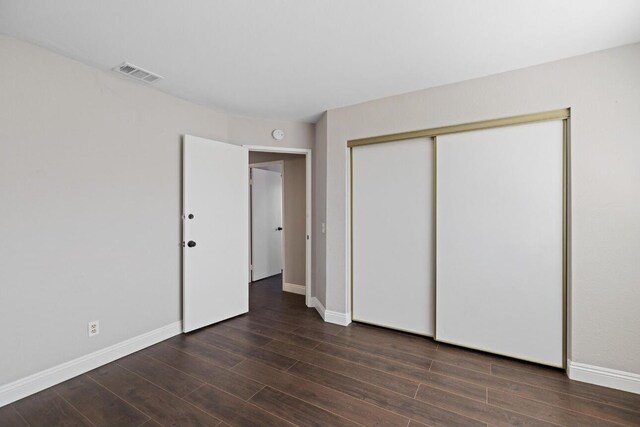 unfurnished bedroom with dark hardwood / wood-style floors and a closet