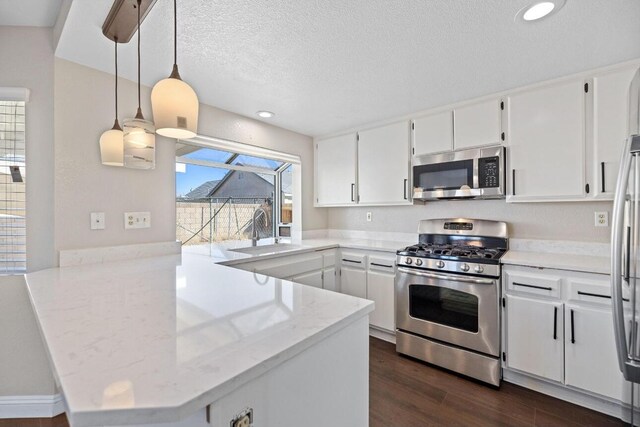 kitchen featuring sink, kitchen peninsula, hanging light fixtures, appliances with stainless steel finishes, and white cabinetry