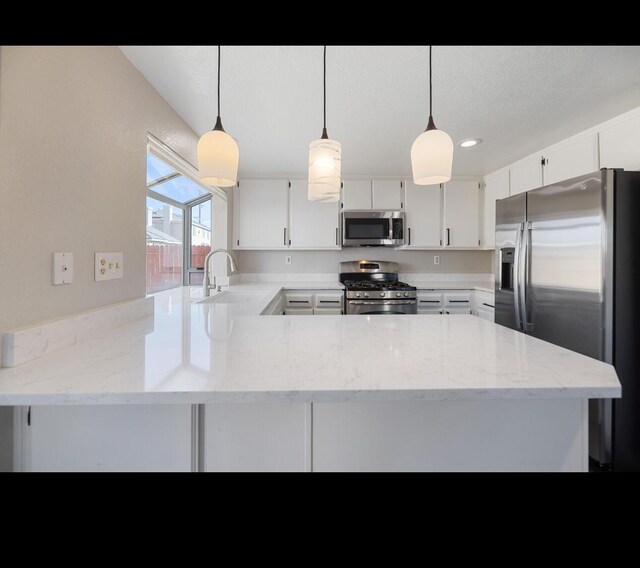 kitchen featuring sink, hanging light fixtures, kitchen peninsula, white cabinets, and appliances with stainless steel finishes