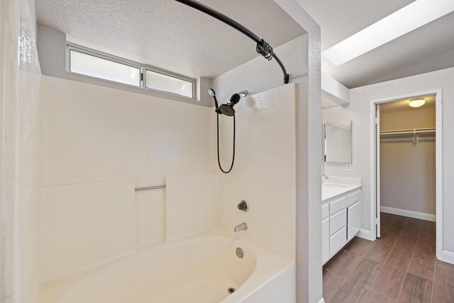 bathroom with a textured ceiling, vanity, and shower / bathtub combination