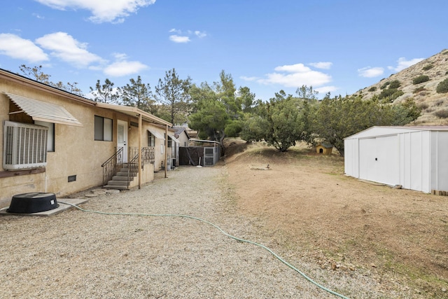 view of yard with an outdoor structure, central AC, and a storage shed