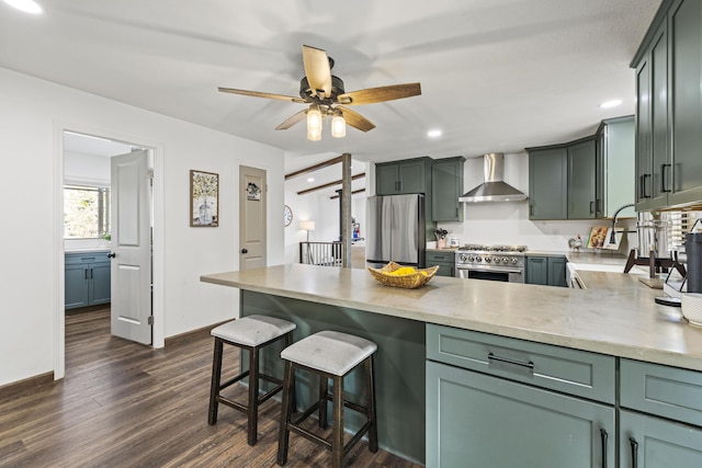 kitchen with a peninsula, ceiling fan, recessed lighting, wall chimney exhaust hood, and appliances with stainless steel finishes