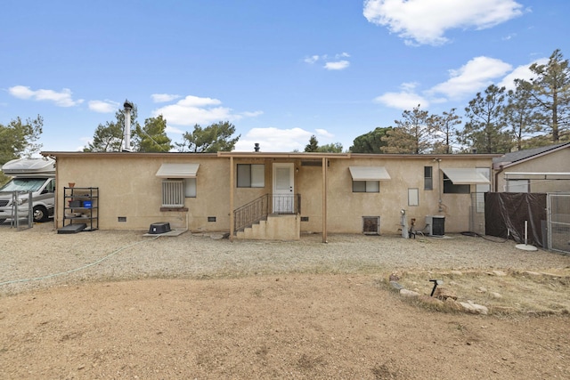 rear view of house with stucco siding, central AC, fence, and crawl space