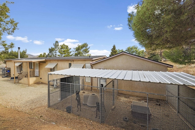 rear view of property with central AC unit, stucco siding, and an outbuilding
