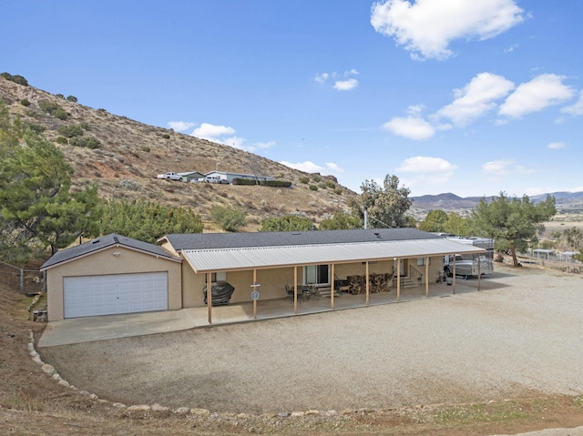 view of front of house featuring a mountain view, stucco siding, metal roof, and dirt driveway