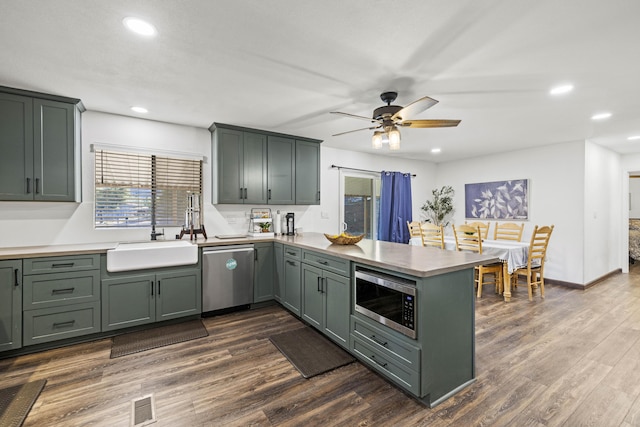 kitchen featuring a sink, stainless steel appliances, a ceiling fan, a peninsula, and visible vents