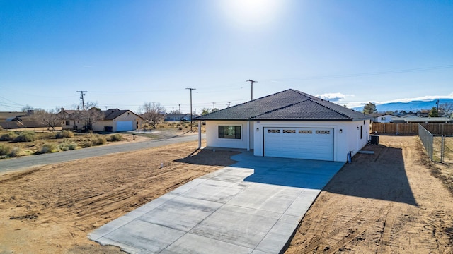 exterior space with a garage, stucco siding, fence, a tile roof, and driveway