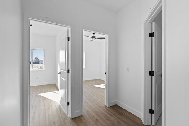 corridor with baseboards and wood finished floors
