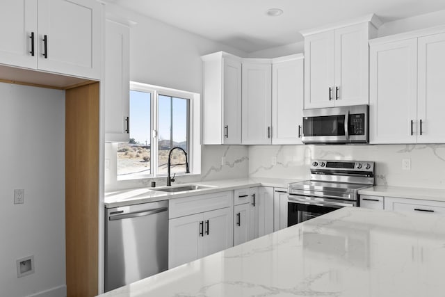 kitchen with tasteful backsplash, appliances with stainless steel finishes, a sink, and light stone counters