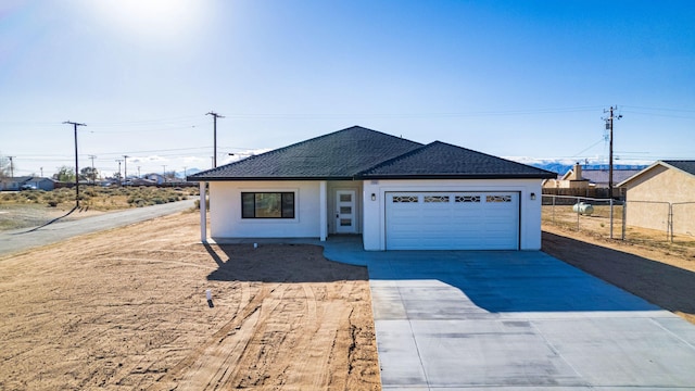 ranch-style house with an attached garage, concrete driveway, fence, stucco siding, and roof with shingles