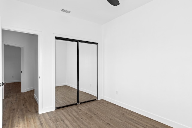 unfurnished bedroom featuring a closet, baseboards, and wood finished floors