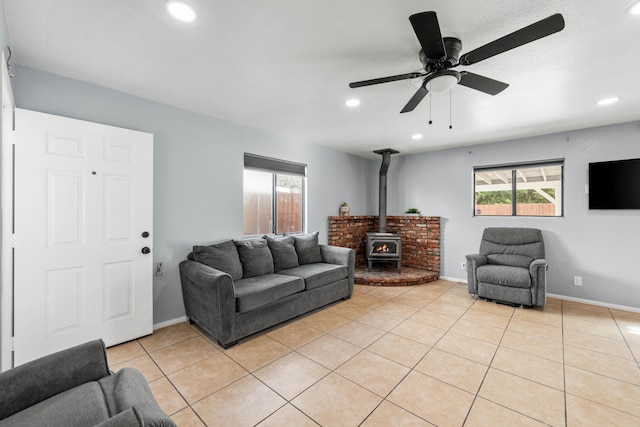 living room featuring recessed lighting, a wood stove, light tile patterned flooring, and a healthy amount of sunlight