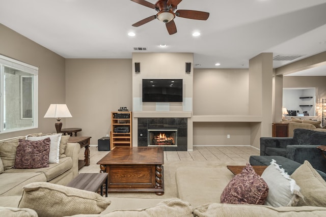 living room featuring a tiled fireplace and ceiling fan