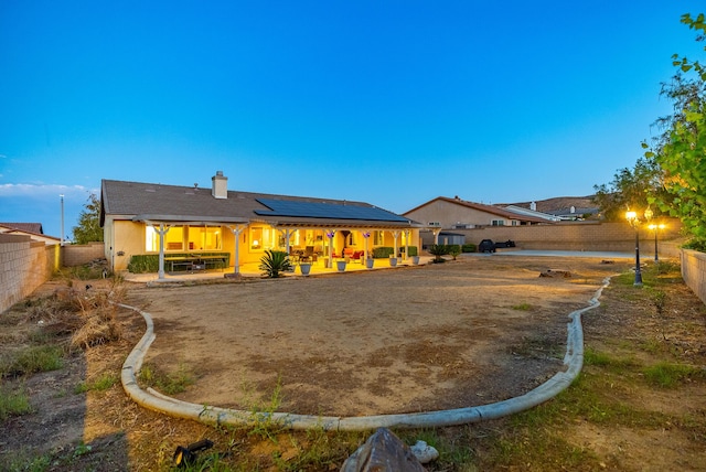 back of property with solar panels and a patio area