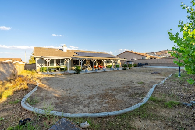 back of property featuring solar panels and a patio area