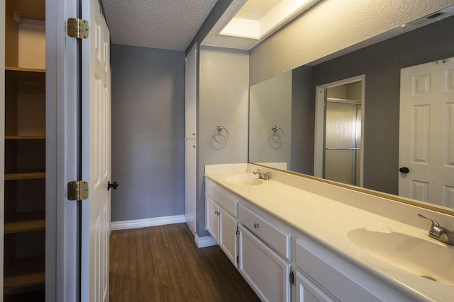 full bath with a sink, double vanity, a stall shower, and wood finished floors