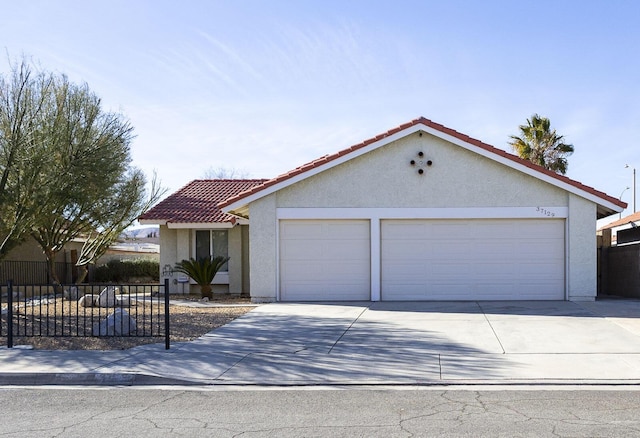 view of front facade featuring fence, stucco siding, concrete driveway, and a tile roof