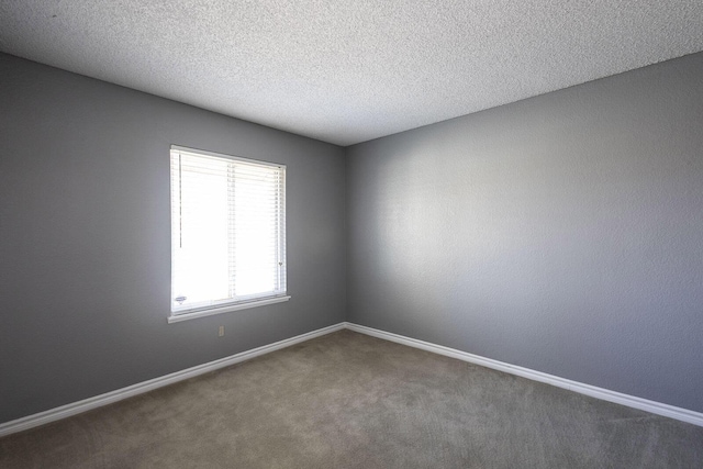carpeted spare room featuring a textured ceiling and baseboards
