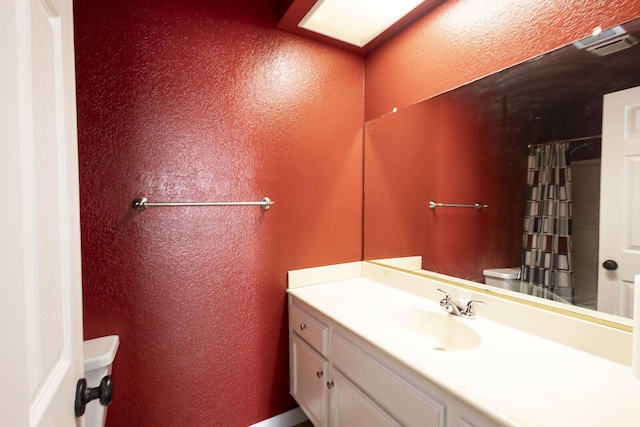 bathroom featuring vanity, a textured wall, toilet, and a shower with shower curtain