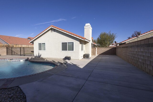 rear view of house with a chimney, central AC, a fenced backyard, a patio, and stucco siding