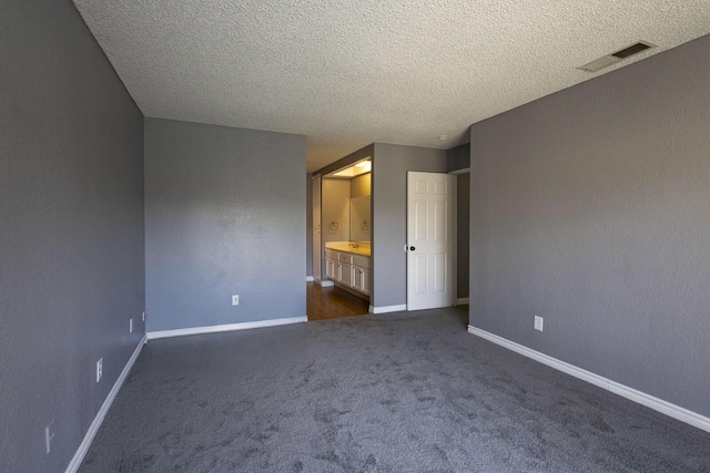 unfurnished bedroom with a textured ceiling, visible vents, baseboards, and dark colored carpet