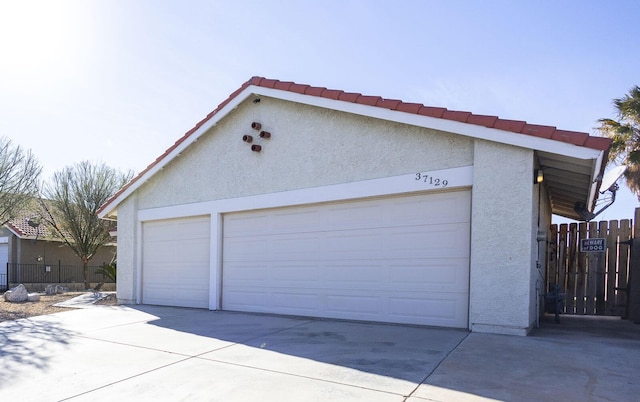 garage with concrete driveway and fence
