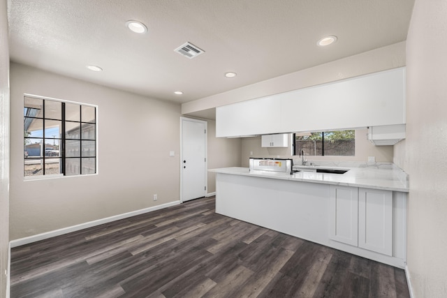 kitchen featuring visible vents, a peninsula, white cabinets, and dark wood finished floors