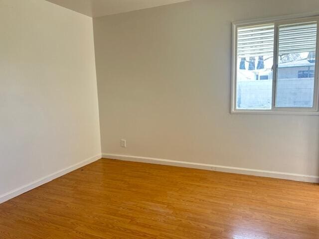 empty room with baseboards, a wealth of natural light, and light wood-type flooring