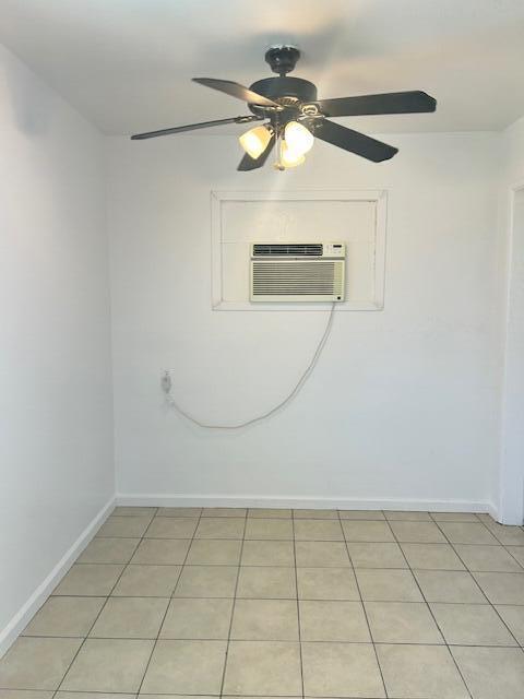 spare room featuring light tile patterned floors, ceiling fan, a wall mounted air conditioner, and baseboards